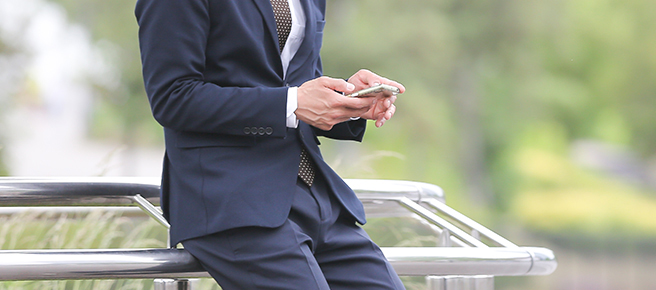 スーツ姿で携帯電話を操作するビジネスマン